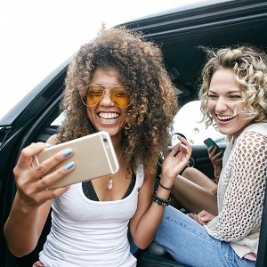 Deux femmes regardant un téléphone portable assis dans la voiture