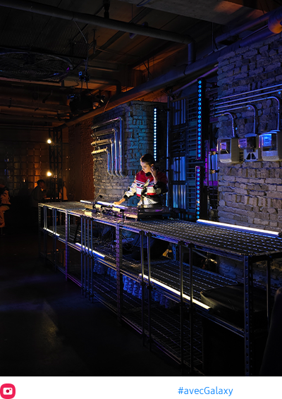 Le Space Zoom est appliqué pour livrer une photo de nuit claire et colorée d’un DJ dans un lounge faiblement éclairé.
